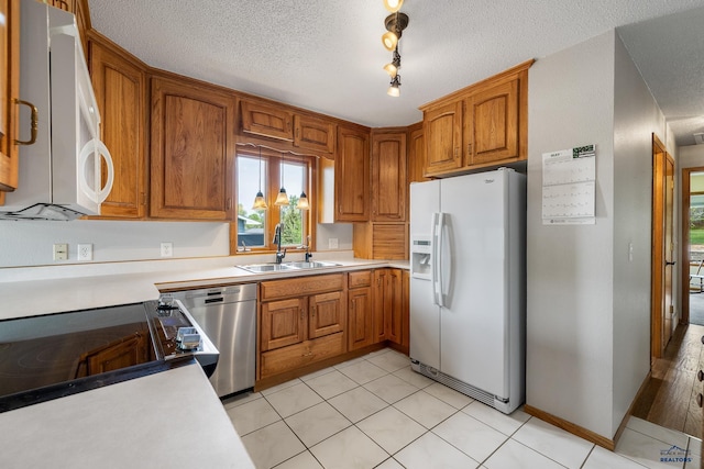 3204 Flint Dr, Rapid City, SD 57702 - kitchen featuring white appliances, a sink, light countertops, brown cabinets, and a textured ceiling