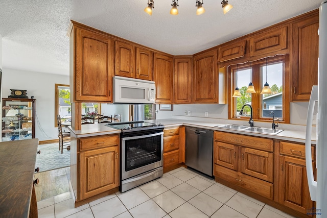 3204 Flint Dr, Rapid City, SD 57702 - kitchen with appliances with stainless steel finishes, a sink, brown cabinetry, a textured ceiling, and light countertops