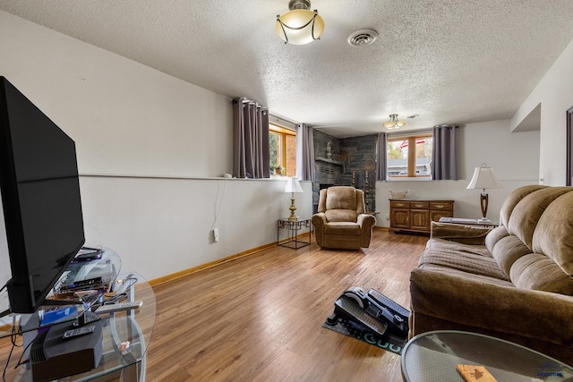 3204 Flint Dr, Rapid City, SD 57702 - living area with wood finished floors, a textured ceiling, a stone fireplace, and baseboards
