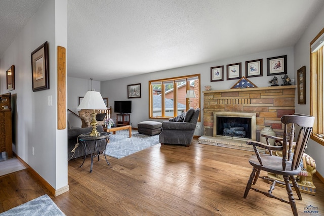 3204 Flint Dr, Rapid City, SD 57702 - living area with a textured ceiling, wood finished floors, a stone fireplace, and baseboards