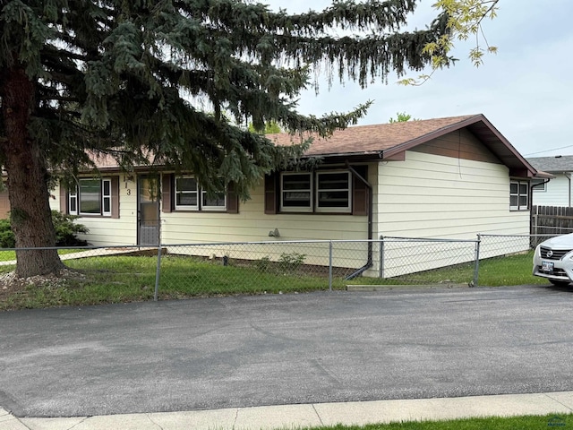single story home with a fenced front yard and a shingled roof