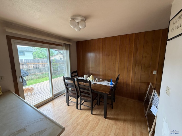 dining area with light wood-style flooring and wood walls