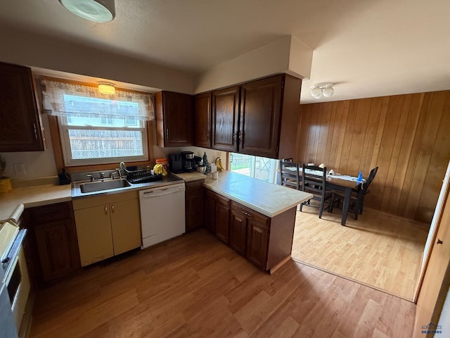 kitchen featuring dishwasher, light wood-style floors, stove, light countertops, and a sink
