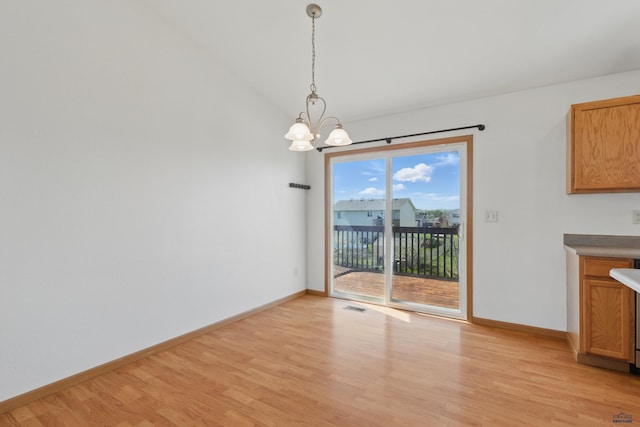 573 Plover Dr, Box Elder, SD 57719 - unfurnished dining area with a chandelier, light wood-style flooring, baseboards, and vaulted ceiling