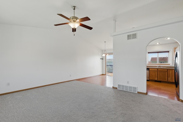 573 Plover Dr, Box Elder, SD 57719 - unfurnished living room with light carpet, ceiling fan, arched walkways, a sink, and baseboards