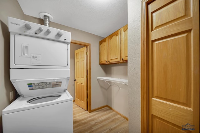 2930 Princeton Ct, Rapid City, SD 57702 - laundry room with stacked washer and clothes dryer, light wood-style floors, baseboards, cabinet space, and a textured ceiling