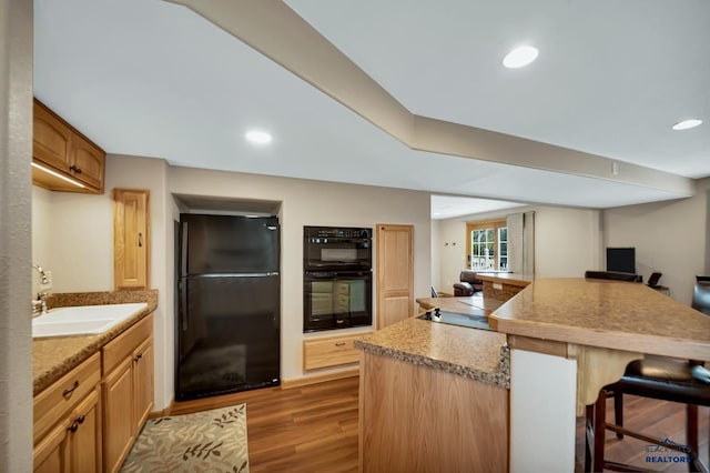 2930 Princeton Ct, Rapid City, SD 57702 - kitchen featuring black appliances, a kitchen bar, a sink, wood finished floors, and recessed lighting