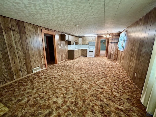 1504 Morningside Dr, Rapid City, SD 57701 - kitchen featuring white electric range oven, wood walls, carpet flooring, a sink, and under cabinet range hood