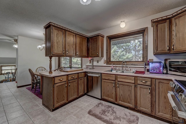 4240 Foothill Dr, Rapid City, SD 57702 - kitchen with a sink, stainless steel appliances, a peninsula, brown cabinetry, and a textured ceiling