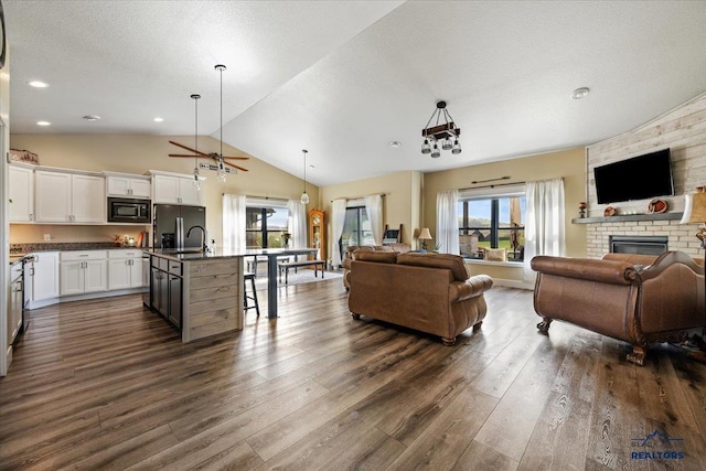 8009 Brooks Loop, Spearfish, SD 57783 - living room featuring lofted ceiling, dark wood finished floors, a fireplace, a ceiling fan, and a textured ceiling