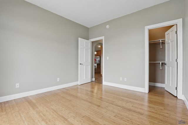 960 Nicole St, Rapid City, SD 57701 - unfurnished bedroom with light wood finished floors, arched walkways, baseboards, a spacious closet, and a closet