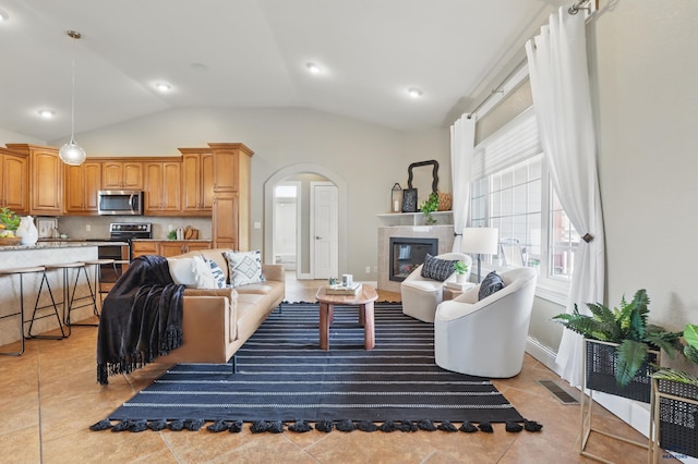 960 Nicole St, Rapid City, SD 57701 - living room with lofted ceiling, a tile fireplace, arched walkways, and light tile patterned floors