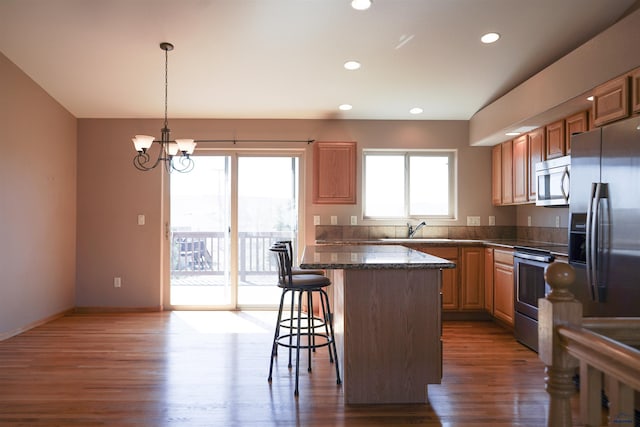 755 Field View Dr, Rapid City, SD 57701 - kitchen featuring stainless steel appliances, a breakfast bar area, a sink, wood finished floors, and a kitchen island