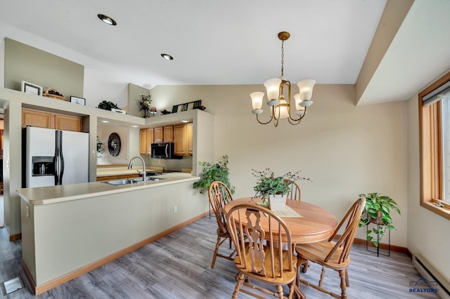 4801 Prairie Rose Pl, Rapid City, SD 57702 - dining room featuring baseboard heating, lofted ceiling, a chandelier, light wood-style flooring, and baseboards
