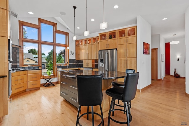 6717 Kennemer Dr, Rapid City, SD 57702 - kitchen with stainless steel fridge, light wood-style flooring, a center island, decorative backsplash, and vaulted ceiling