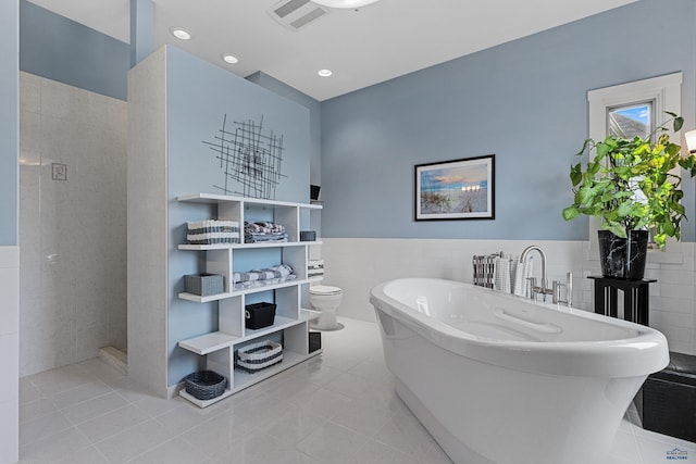6717 Kennemer Dr, Rapid City, SD 57702 - bathroom with tile walls, tile patterned floors, a freestanding tub, wainscoting, and toilet