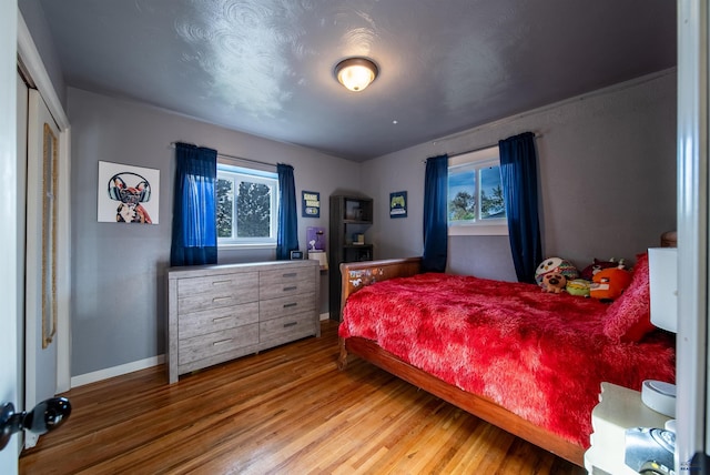 1421 12th Ave, Belle Fourche, SD 57717 - bedroom with wood finished floors, multiple windows, baseboards, and a closet