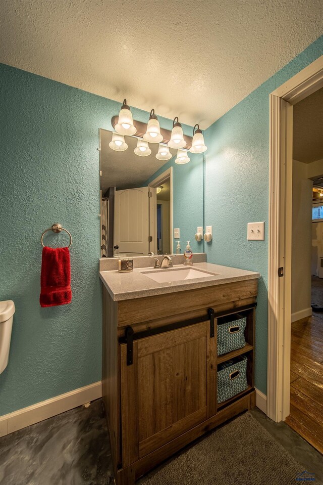 1421 12th Ave, Belle Fourche, SD 57717 - bathroom featuring a textured wall, a textured ceiling, vanity, and baseboards