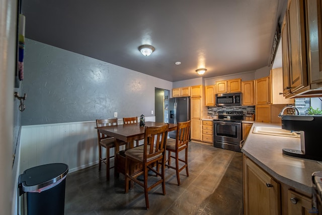 1421 12th Ave, Belle Fourche, SD 57717 - kitchen with stainless steel appliances, a sink, backsplash, wainscoting, and dark countertops