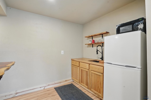 385 15th St, Sturgis, SD 57785 - kitchen featuring freestanding refrigerator, black microwave, a sink, light wood-style flooring, and open shelves