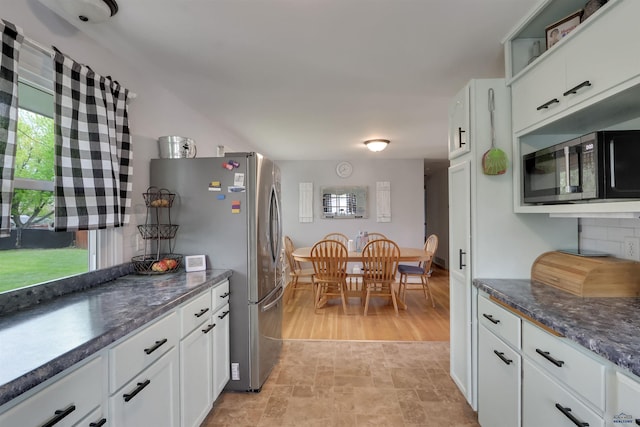 712 Stanley, Belle Fourche, SD 57717 - kitchen with black microwave, white cabinets, freestanding refrigerator, and plenty of natural light
