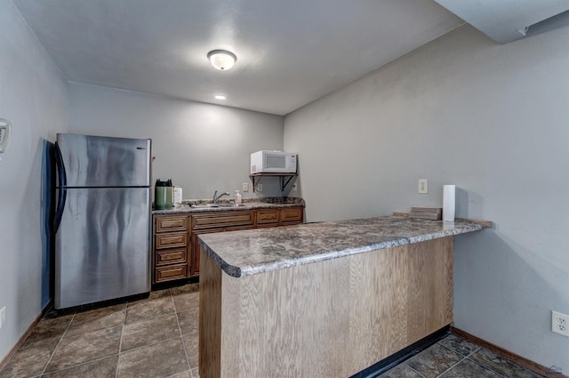 3968 Fairway Hills Dr, Rapid City, SD 57702 - kitchen with freestanding refrigerator, white microwave, a peninsula, baseboards, and a sink