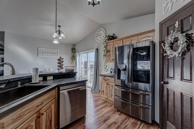 22970 Candlelight Dr, Rapid City, SD 57703 - kitchen with stainless steel appliances, vaulted ceiling, dark countertops, a sink, and light wood-type flooring