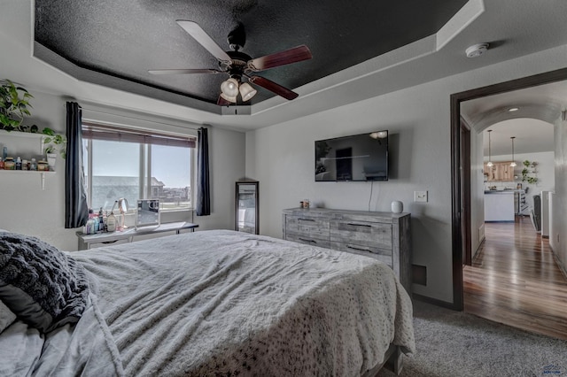 22970 Candlelight Dr, Rapid City, SD 57703 - bedroom featuring a raised ceiling, baseboards, ceiling fan, light colored carpet, and a textured ceiling