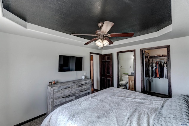 22970 Candlelight Dr, Rapid City, SD 57703 - bedroom featuring baseboards, carpet flooring, a tray ceiling, and a walk in closet