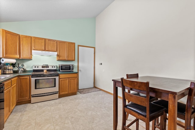 5436 Weathervane Ln, Rapid City, SD 57703 - kitchen with stainless steel appliances, under cabinet range hood, high vaulted ceiling, dark countertops, and brown cabinets