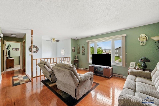 720 S 32nd, Spearfish, SD 57783 - living room featuring light wood-type flooring, baseboard heating, a textured ceiling, a ceiling fan, and baseboards