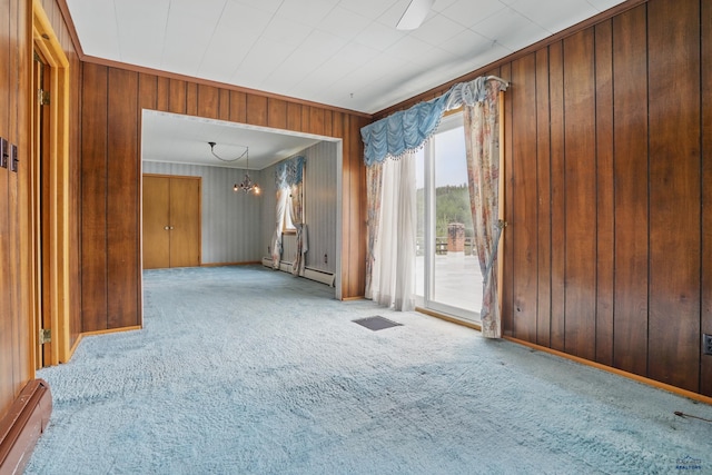 12384 Stannum Pl, Hill City, SD 57745 - spare room featuring a chandelier, carpet floors, wood walls, a baseboard heating unit, and baseboards
