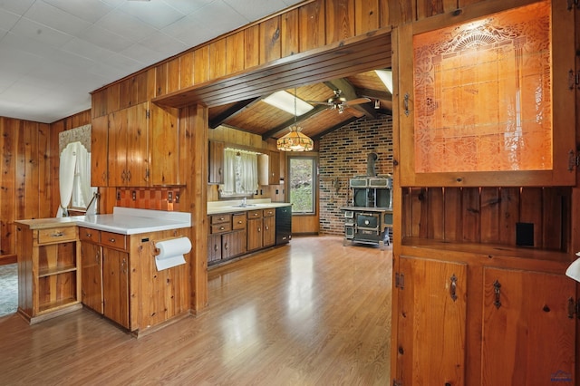 12384 Stannum Pl, Hill City, SD 57745 - kitchen with a wood stove, brown cabinetry, light wood-style flooring, light countertops, and wooden walls