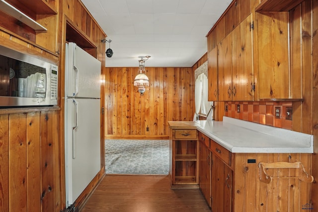 12384 Stannum Pl, Hill City, SD 57745 - kitchen featuring stainless steel microwave, freestanding refrigerator, brown cabinetry, light countertops, and dark wood-style floors