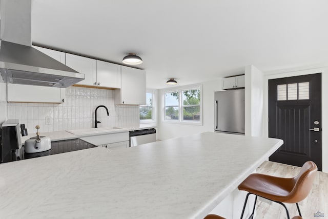 726 Willsie Ave, Rapid City, SD 57701 - kitchen with freestanding refrigerator, wall chimney range hood, dishwashing machine, a sink, and light countertops