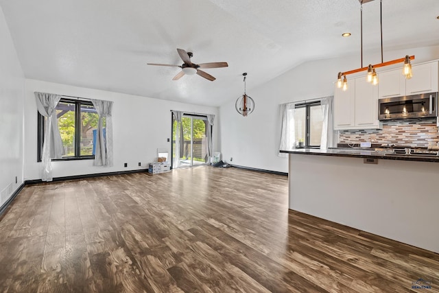 1215 Range View Cir, Rapid City, SD 57701 - unfurnished living room with a ceiling fan, lofted ceiling, healthy amount of natural light, dark wood-style flooring, and baseboards