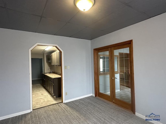 414 2nd Ave, Edgemont, SD 57735 - empty room with french doors, light carpet, arched walkways, baseboards, and a sink