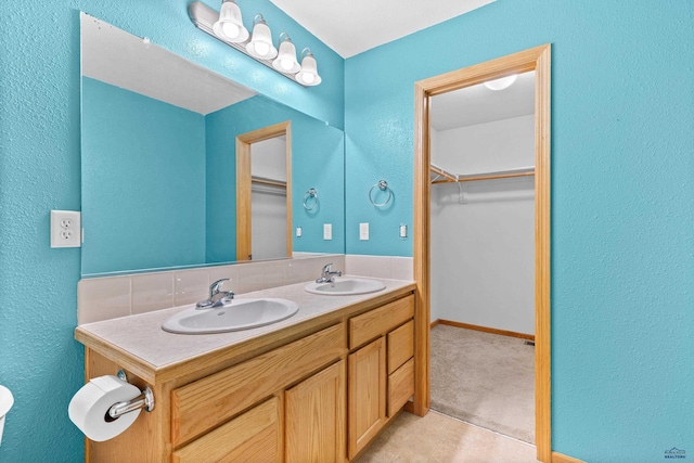 4300 Donegal Way, Rapid City, SD 57702 - bathroom featuring double vanity, a spacious closet, a textured wall, and baseboards