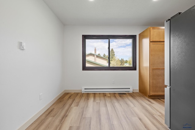 248 S 10th St, Custer, SD 57730 - unfurnished bedroom with a baseboard heating unit, freestanding refrigerator, light wood-style floors, and baseboards