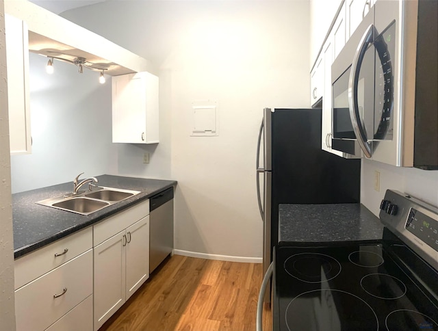 305 S Canyon Rd Unit 8D, Rapid City, SD 57702 - kitchen featuring appliances with stainless steel finishes, a sink, dark countertops, light wood finished floors, and white cabinets