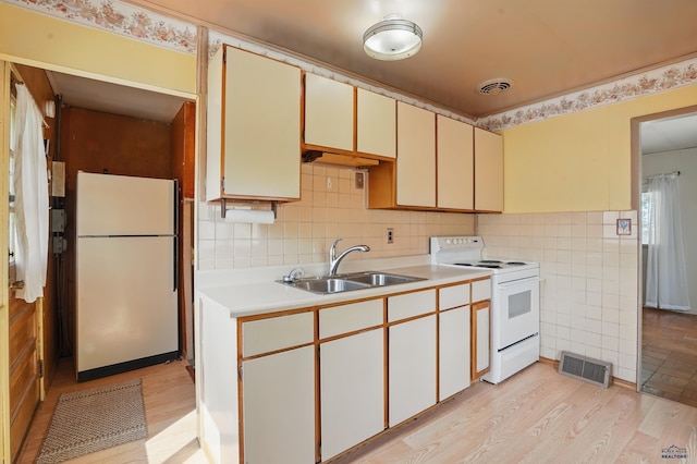 1905 5th St, Rapid City, SD 57701 - kitchen featuring white appliances, a sink, light countertops, light wood finished floors, and tile walls