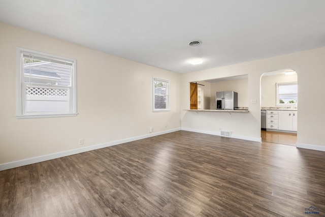 814 Flormann, Rapid City, SD 57701 - unfurnished living room with plenty of natural light, dark wood-style floors, arched walkways, and baseboards