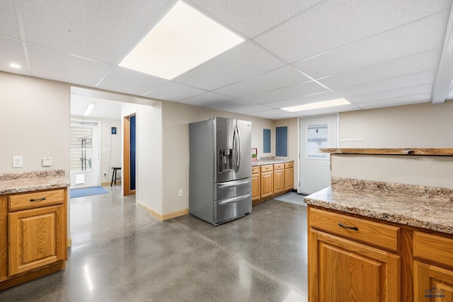 814 Flormann, Rapid City, SD 57701 - kitchen with stainless steel refrigerator with ice dispenser, a paneled ceiling, brown cabinetry, baseboards, and light countertops