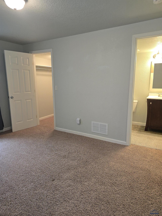 14655 Telluride St, Summerset, SD 57769 - unfurnished bedroom with a spacious closet, carpet floors, baseboards, ensuite bathroom, and a textured ceiling