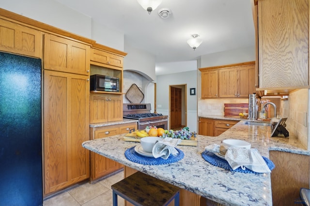902 Fulton St, Rapid City, SD 57701 - kitchen with black appliances, a peninsula, light stone countertops, decorative backsplash, and a sink