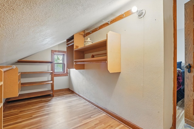 902 Fulton St, Rapid City, SD 57701 - additional living space featuring a textured ceiling, a textured wall, wood finished floors, lofted ceiling, and baseboards