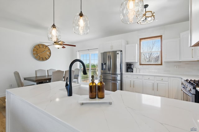 7155 Mulberry Dr, Summerset, SD 57718 - kitchen with appliances with stainless steel finishes, light stone countertops, white cabinets, tasteful backsplash, and pendant lighting