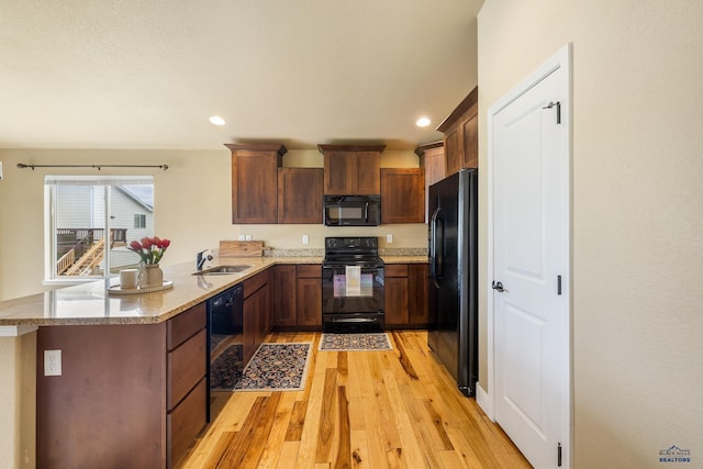 3216 Eunice Dr, Rapid City, SD 57703 - kitchen with black appliances, light wood-style flooring, a peninsula, light stone counters, and recessed lighting