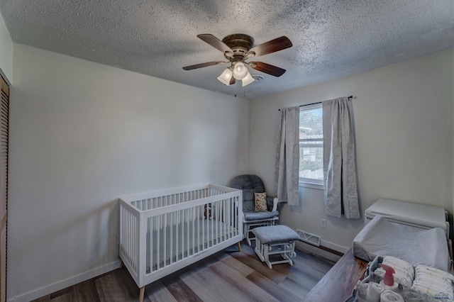 426 E Oakland, Rapid City, SD 57701 - bedroom featuring wood finished floors, baseboards, a textured ceiling, ceiling fan, and a crib