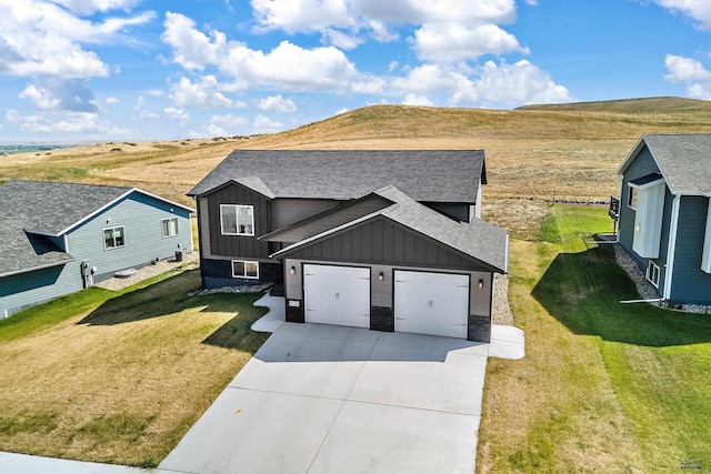 3123 Caymus Dr, Rapid City, SD 57703 - view of front of property featuring board and batten siding, concrete driveway, roof with shingles, a front lawn, and a mountain view